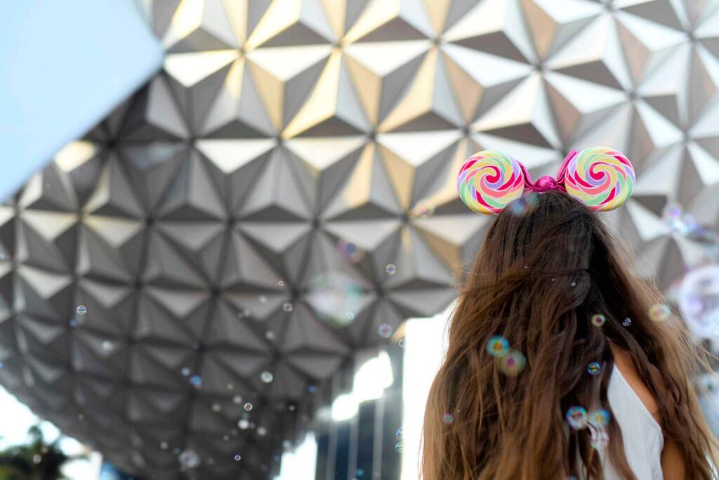 Transportation 2 Girl wearing candy themed Minnie Mouse ears looking up at Spaceship Earth in EPCOT | Walt Disney World