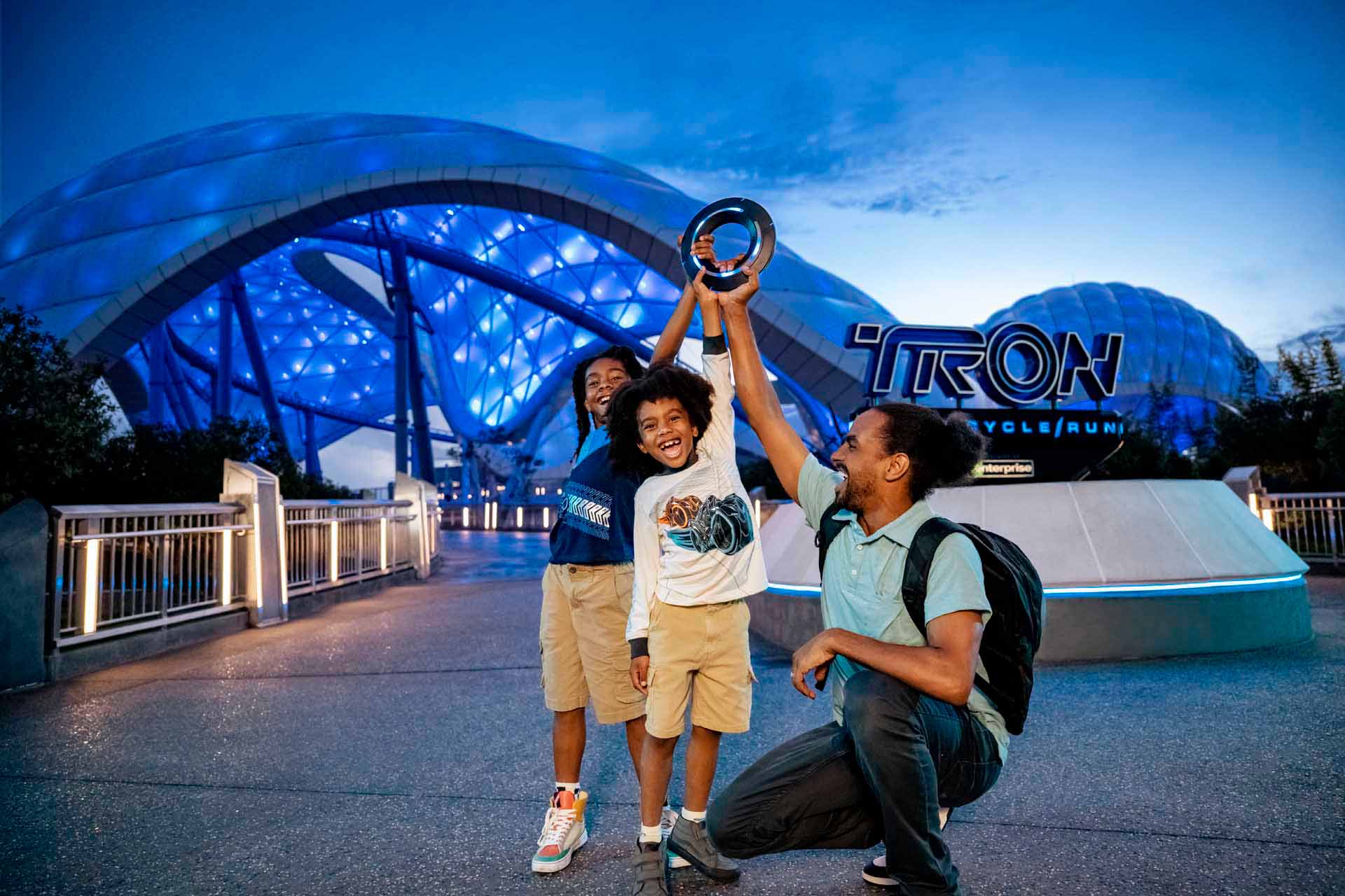 Happy family in front of Tron Lightcycle Run roller coaster at the Magic Kingdom