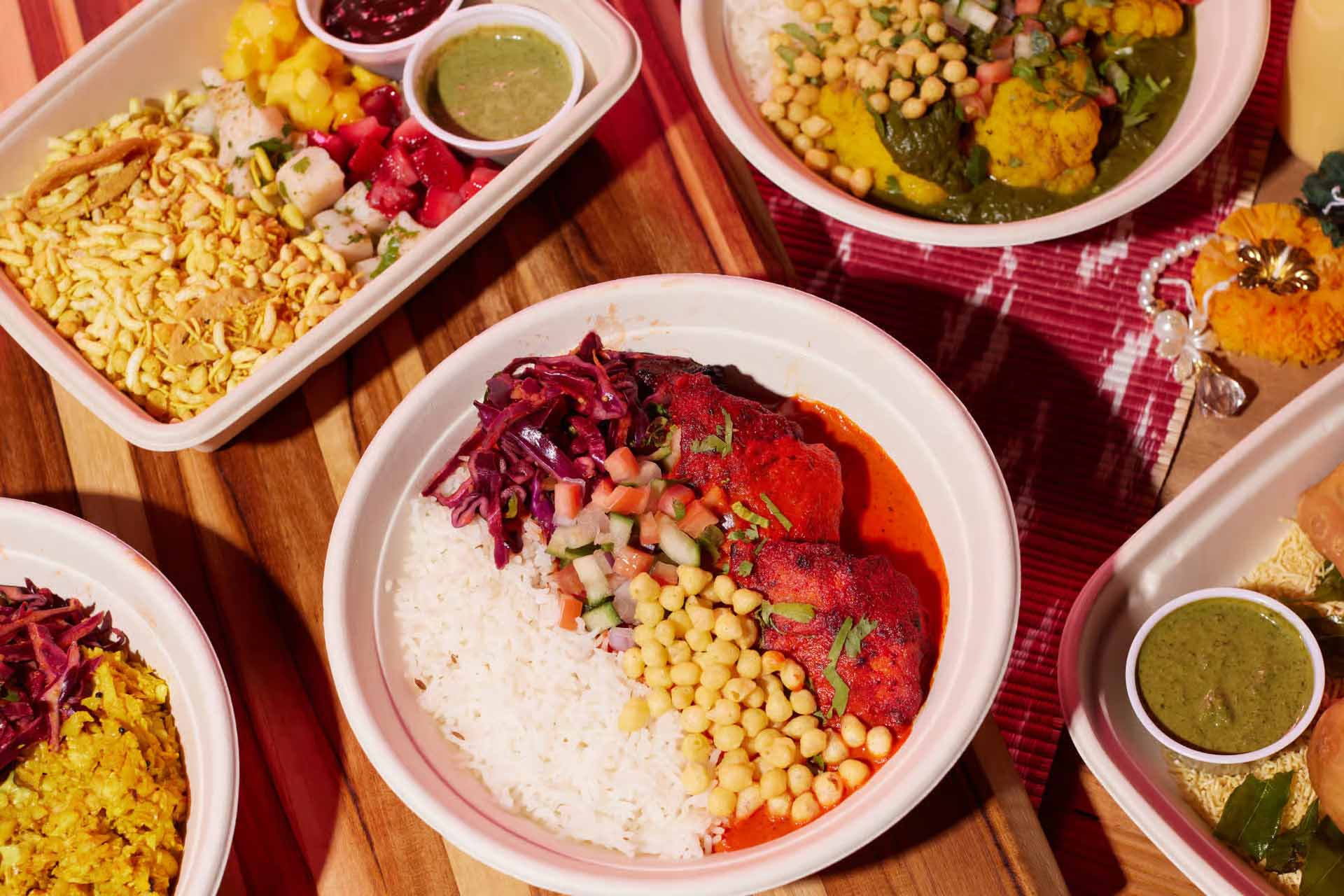 Various Indian inspired meals, plated in paper plates on a table