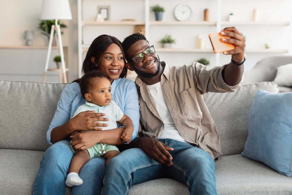 Family of three taking a selfie on their living room couch