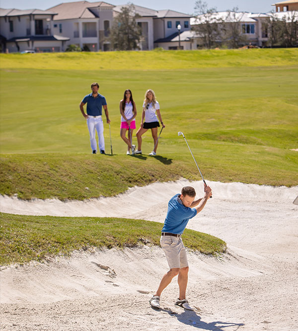 Golfer attempts to hit out of a sand trap on the Jack Nicklaus course while 3 friends watch.