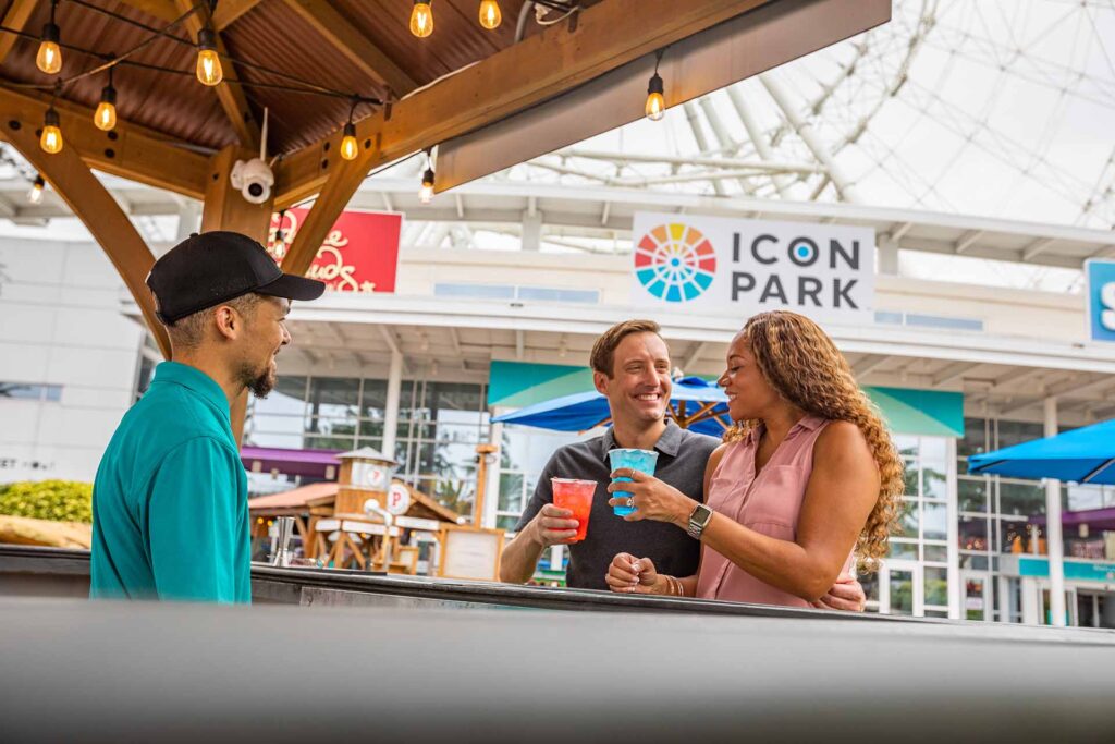 Couple enjoying colorful cocktails at a bar in ICON Park