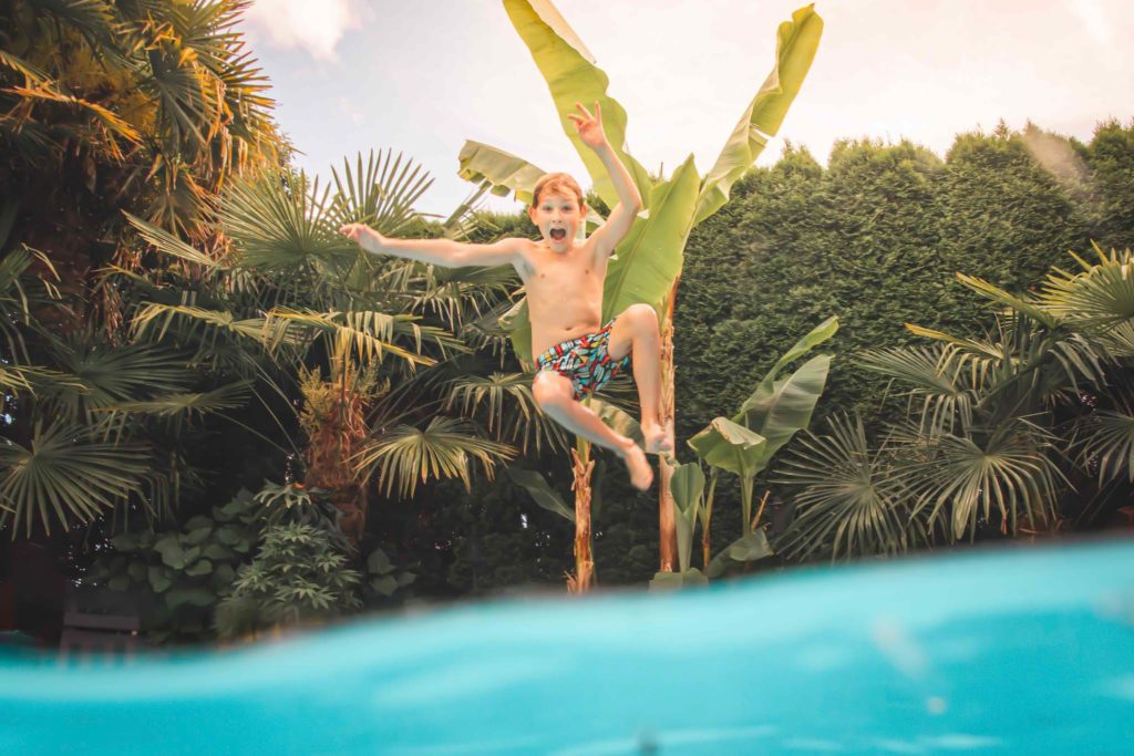 Happy kid jumping into a swimming pool.