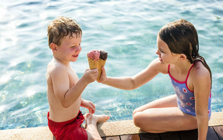 Kids toasting with ice creams at the poolside