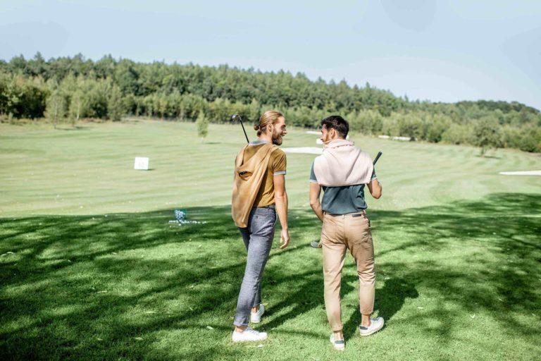 Male friends chatting with one another on a golf course