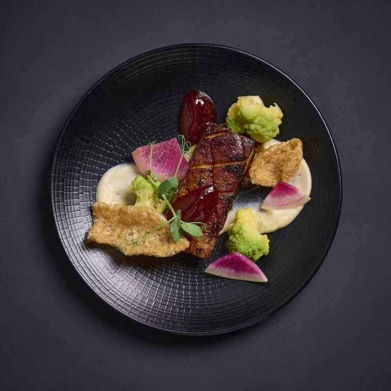 Meticulously plated fresh grilled fish fillet with assorted vegetables and sauces
