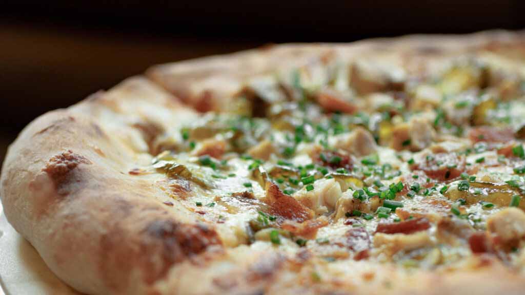 Close up of an artisan pizza topped with bacon and chives