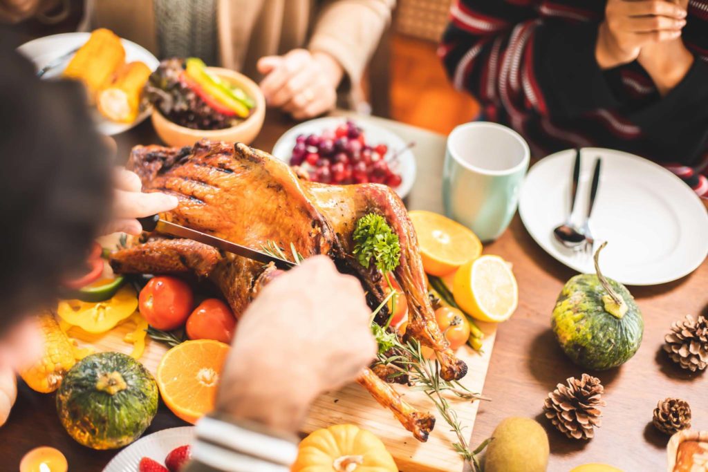 Family having Thanksgiving dinner and cutting turkey.