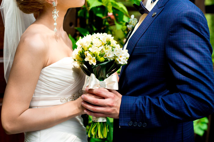 Bride and groom dance while holding bridal bouquet.